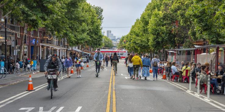 A slow street in San Francisco where pedestrians are walking, biking and scootering.
