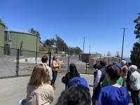 crowd of people looking at tour guide in front of water treatment facility 